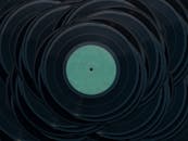 A top view of stacked vintage vinyl records creating an artistic pattern with a moody tone.